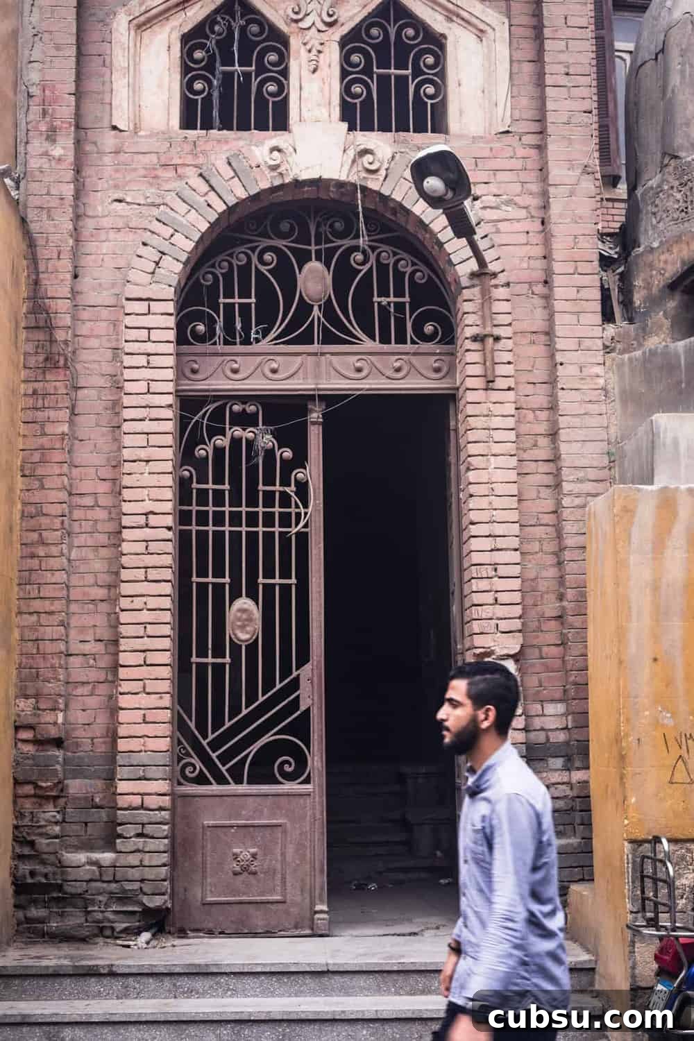 Cairo Adventures: Top Experiences and Hidden Gems to Explore 8 Man passing a gorgeous old gate in Old Cairo.