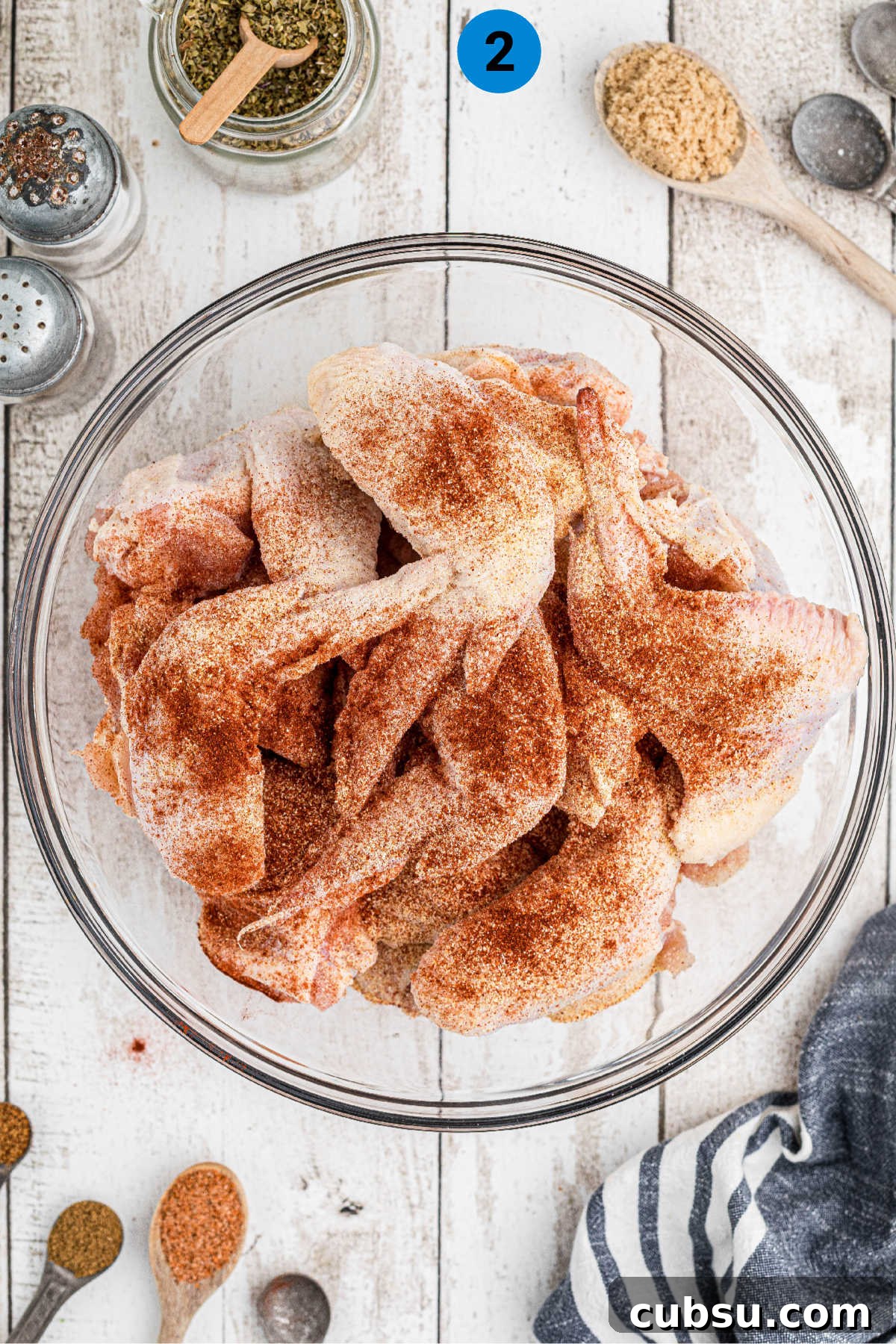 Chicken wings in a bowl with seasoning sprinkled on top.