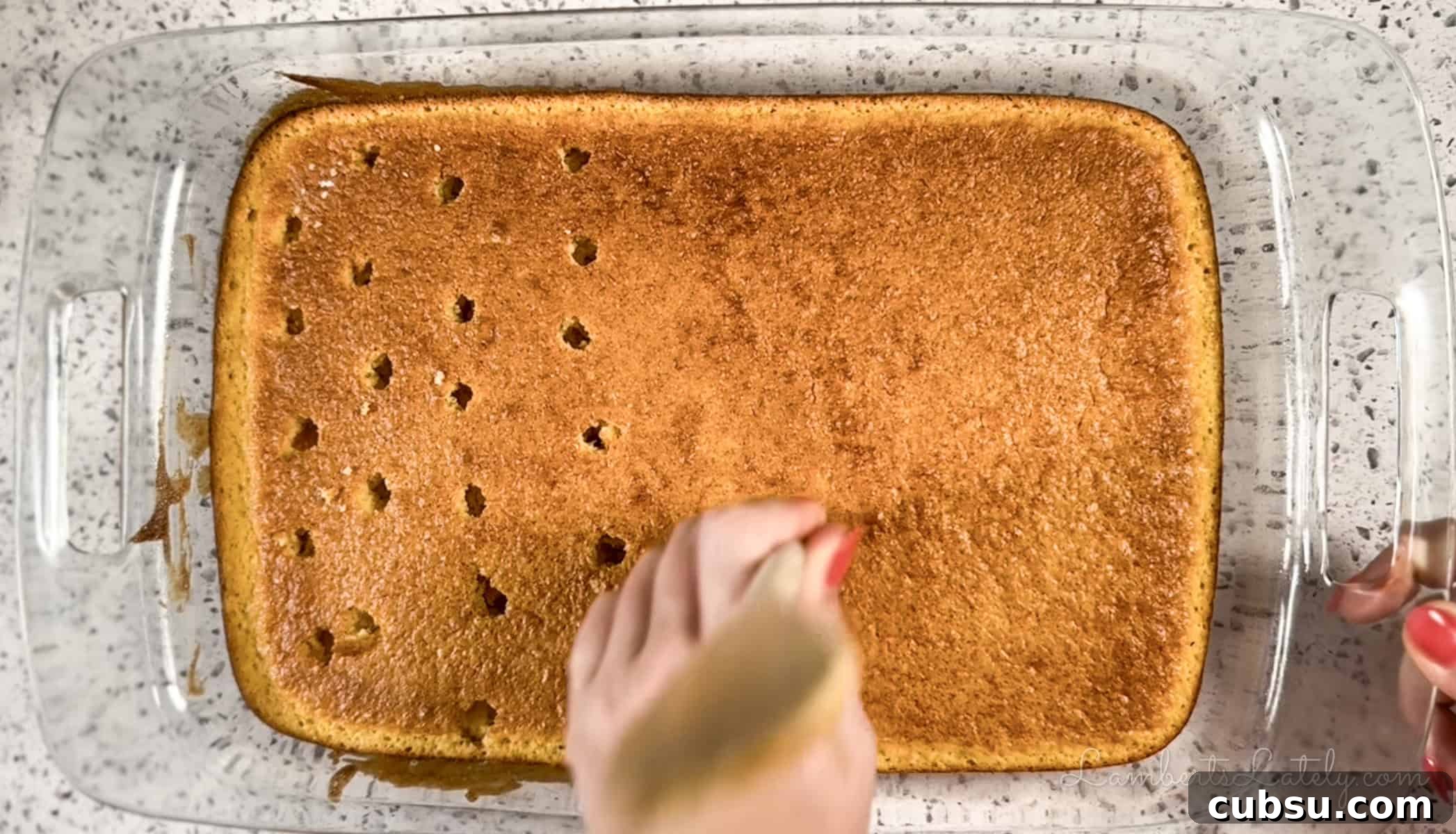 poking holes in a sheet cake with the back of a wooden spoon.