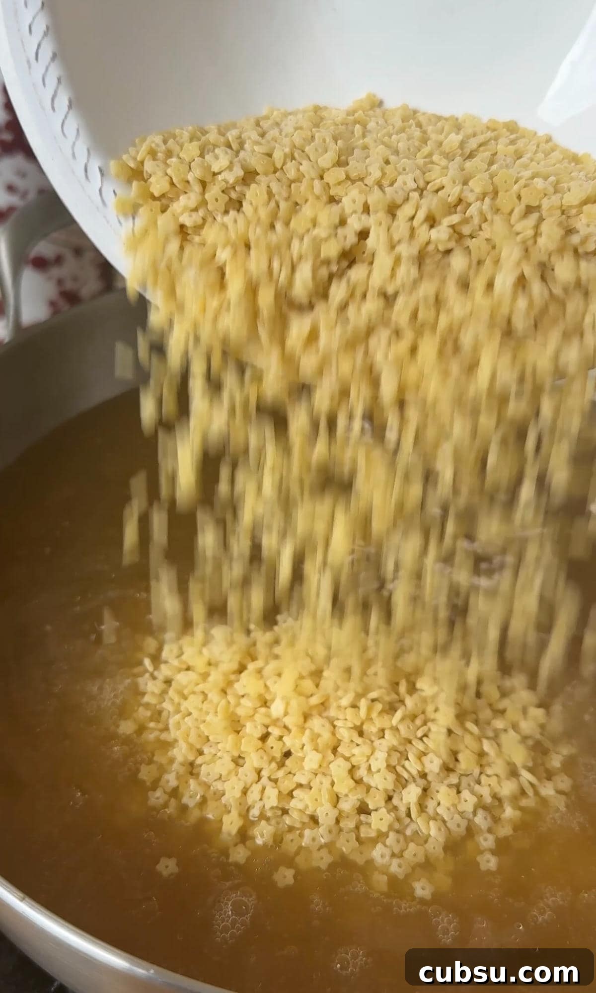 Creamy Pastina Recipe: Quick Comfort Pasta in 20 Minutes 5 pouring pastina into chicken stock.