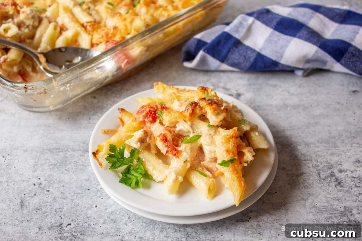 Chicken pasta with tomatoes and topped with fresh green parsley.