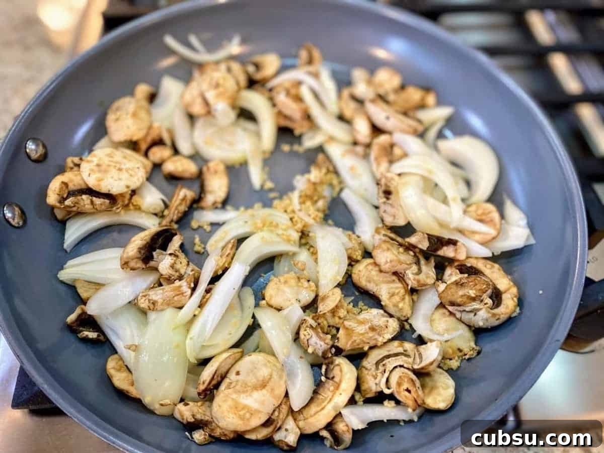 Vegan Pesto Pasta Recipe with Creamy Cashew Sauce 3 I am cooking garlic, onions, and mushrooms on the stove.