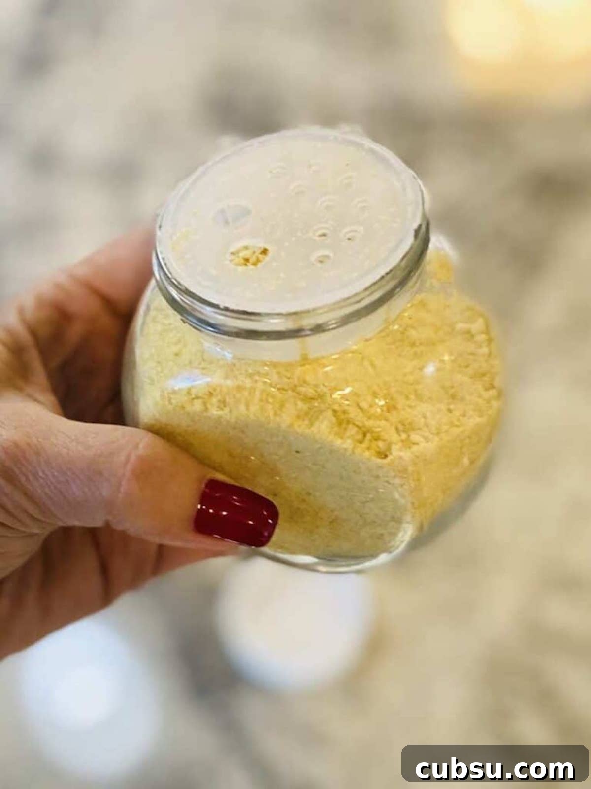 Vegan Pesto Pasta Recipe with Creamy Cashew Sauce 5 I am holding vegan parmesan cheese in a container.