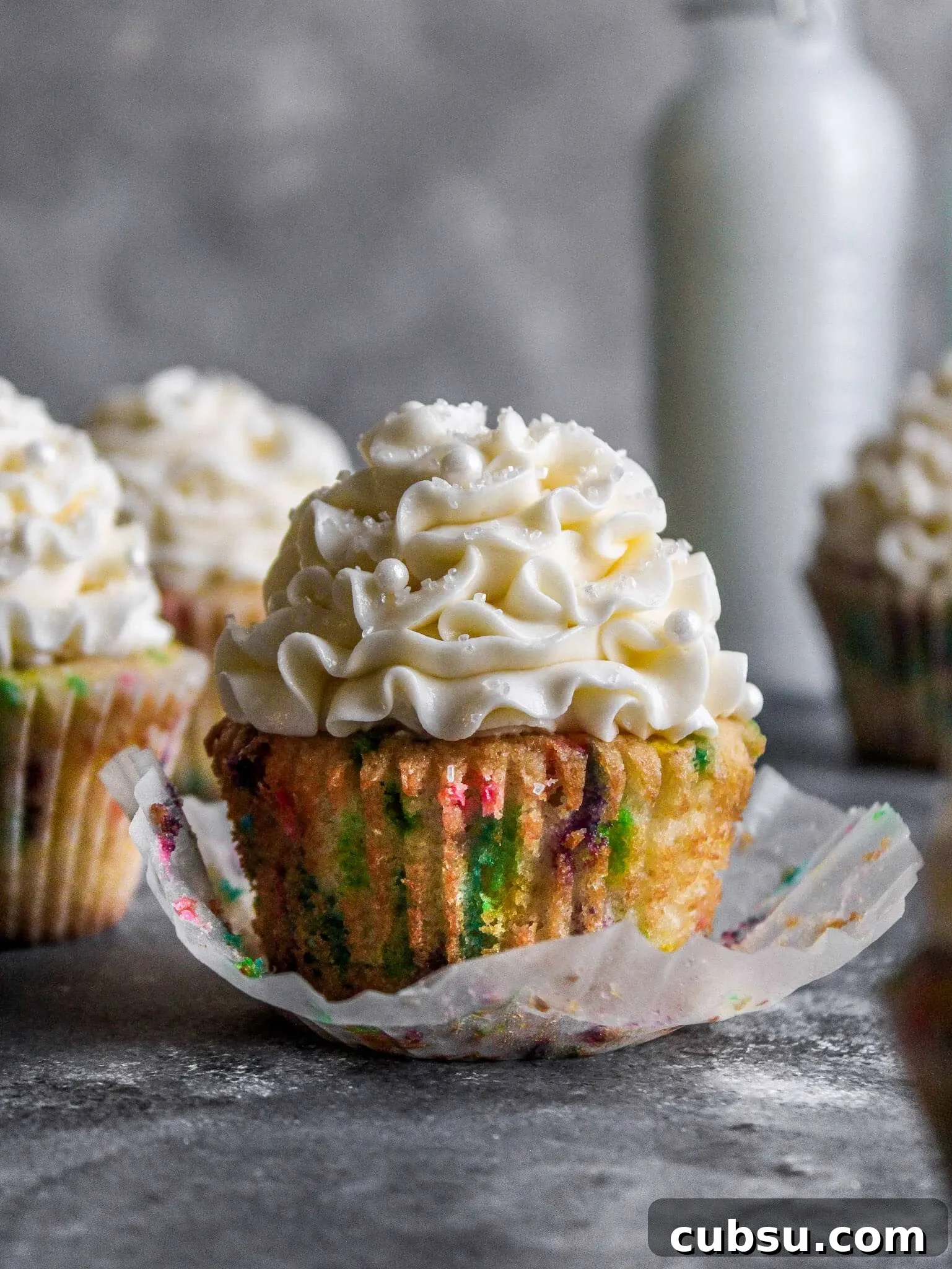 Muffins vs Cupcakes: Key Differences, Taste & Baking Tips 7 frosted funfetti cupcakes on table with cupcake unwraped (1)