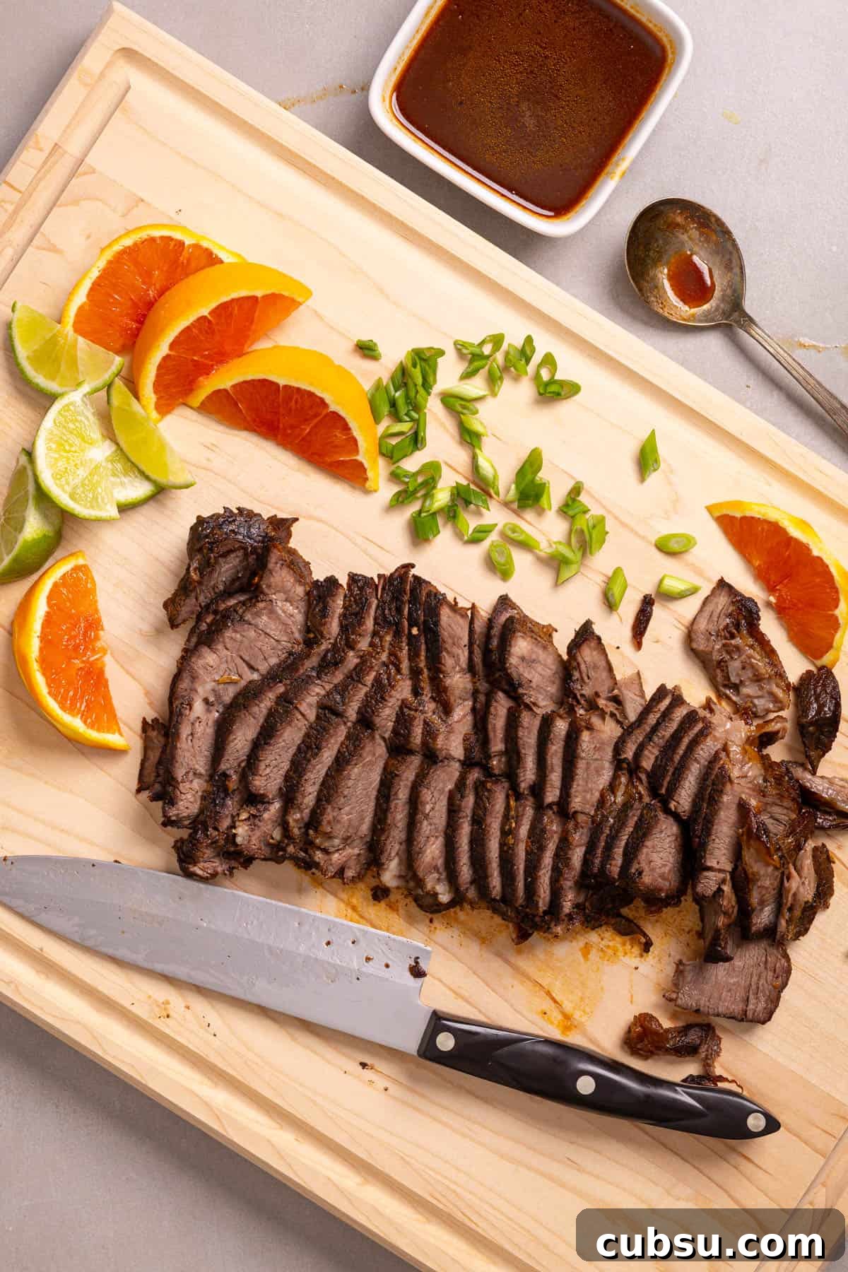 Citrus Slaw Braised Beef Sliders – Tangy Gourmet Sandwiches 5 A cutting board with sliced of orange and lime, scallions, and braised chuck roast.