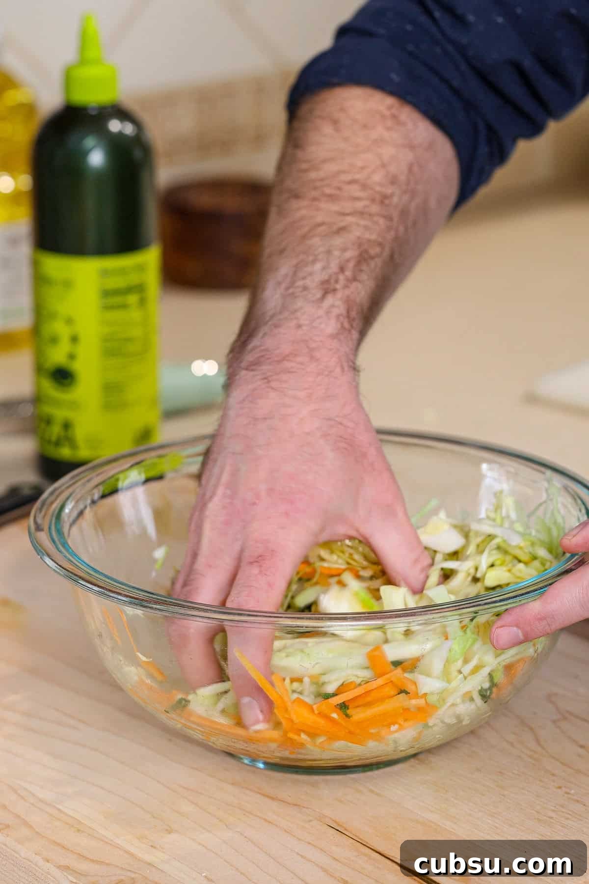 Citrus Slaw Braised Beef Sliders – Tangy Gourmet Sandwiches 7 A hand mixing a cabbage and carrots for a citrus slaw.