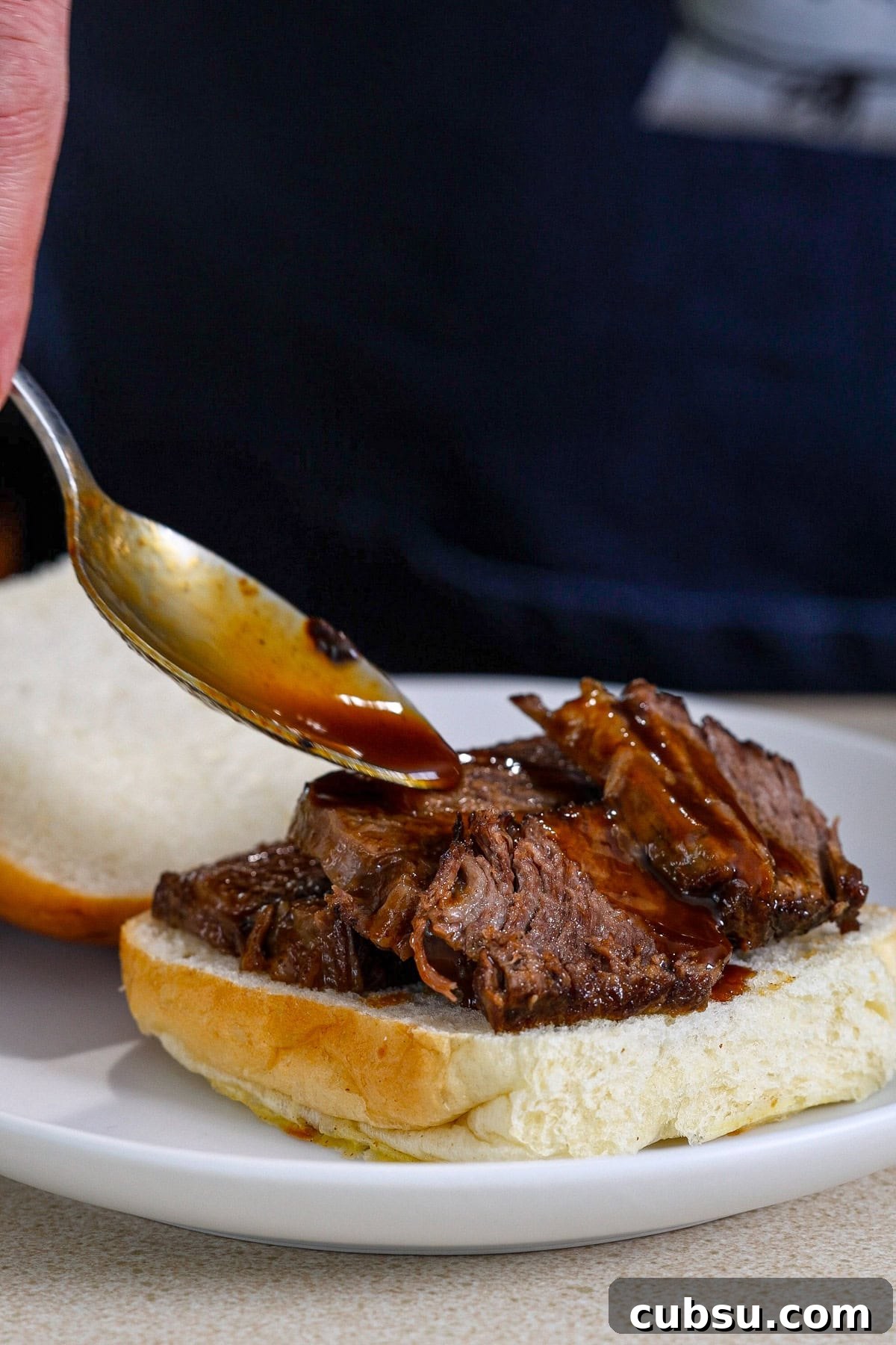 Citrus Slaw Braised Beef Sliders – Tangy Gourmet Sandwiches 8 A rich sauce getting spooned over braised beef sliders.