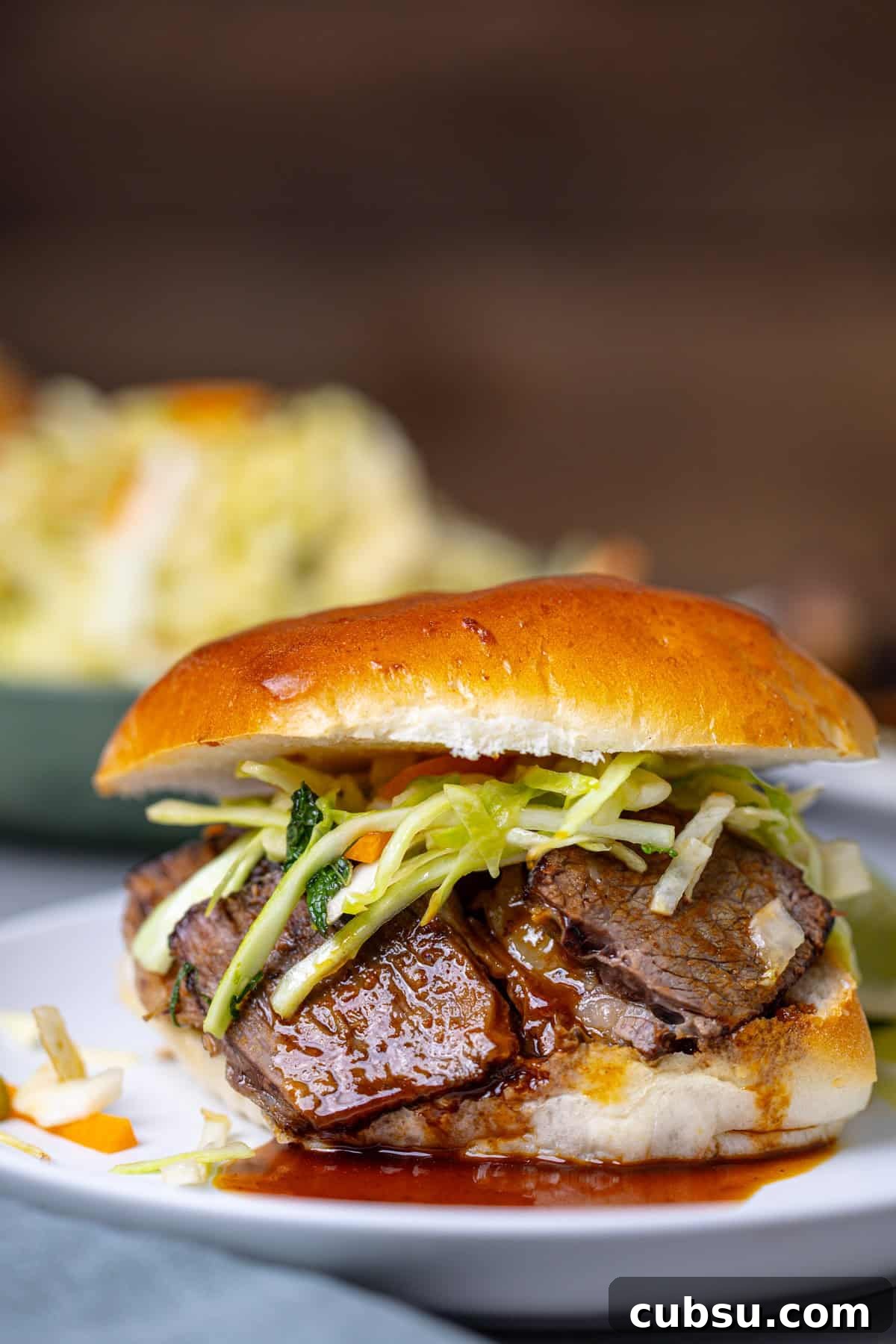 Citrus Slaw Braised Beef Sliders – Tangy Gourmet Sandwiches 10 A close up shot of a single braised beef slider topped with citrus slaw.
