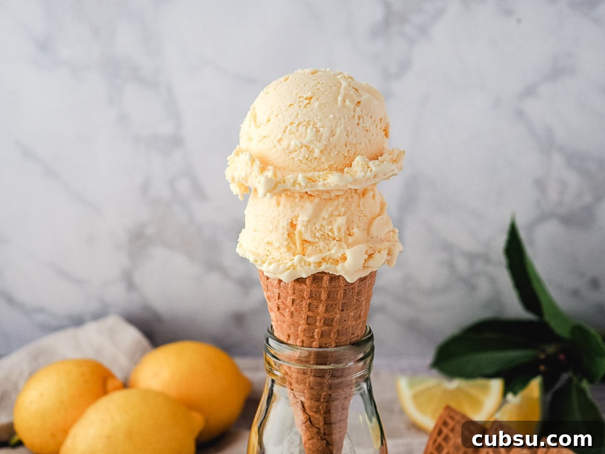 Creamy Lemon Ice Cream Recipe: Bright, Tangy Homemade Treat 8 Two scoops of ice cream in a cone, with fresh lemons in the background.