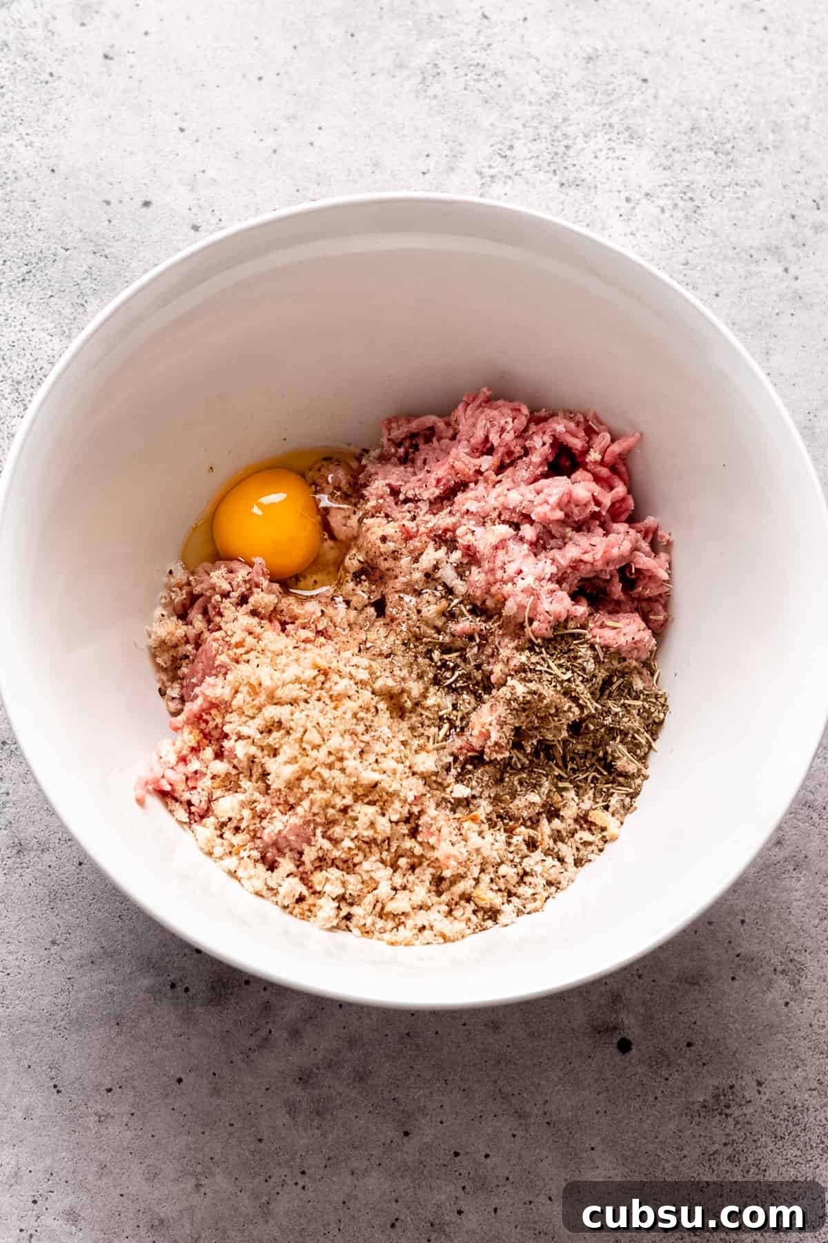Classic Greek Meatballs Recipe (Keftedes) for Authentic Flavor 3 Meatball mixture in a bowl with breadcrumbs and egg.