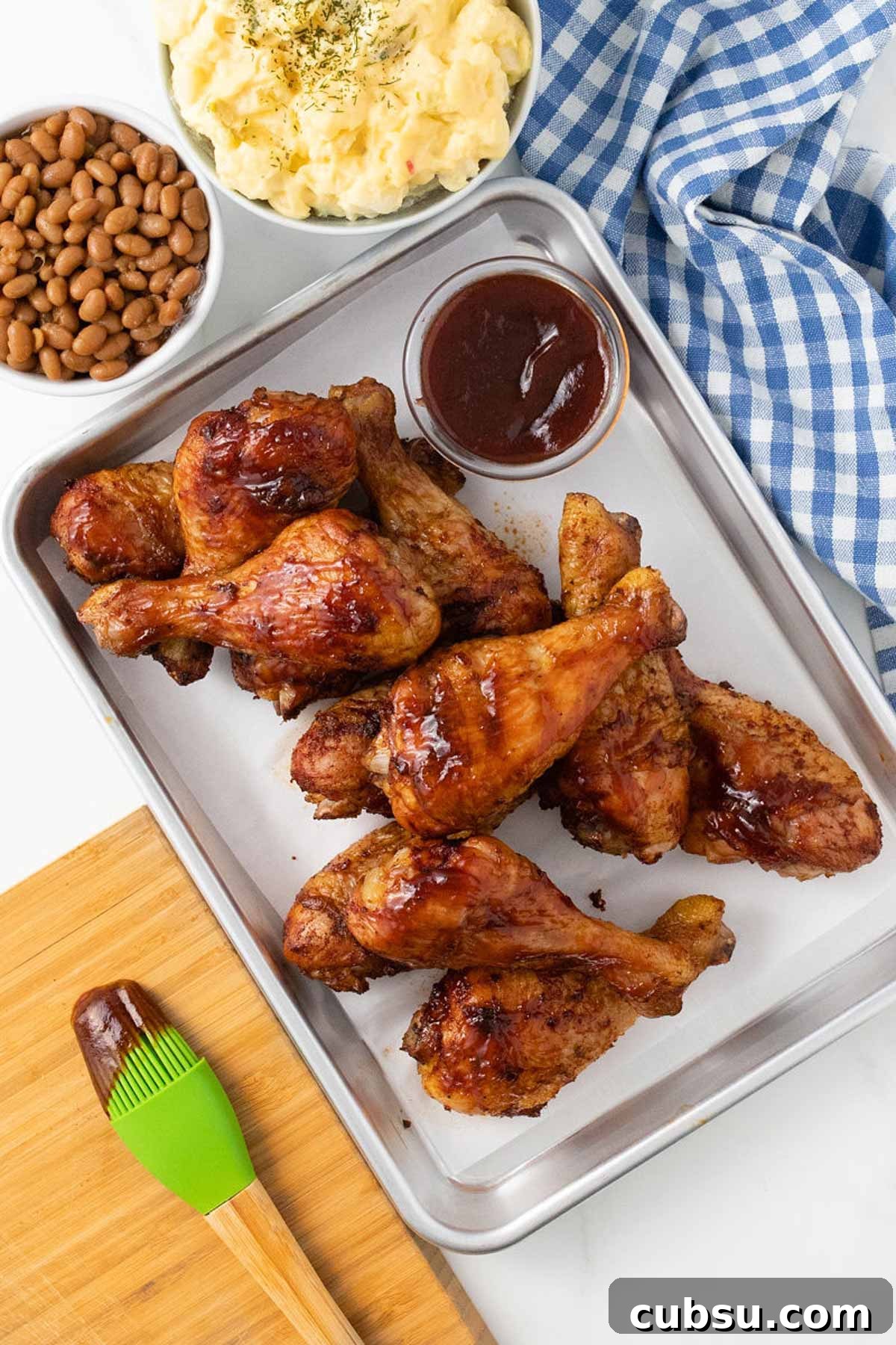 Chicken legs after cooking on a baking tray to brush with bbq sauce.