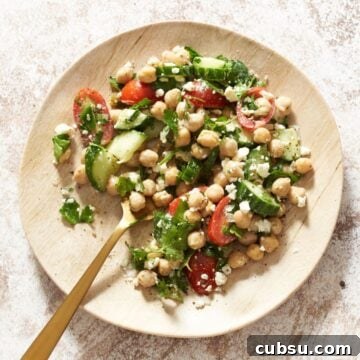 A small plate of garbanzo bean salad with a gold fork in it.