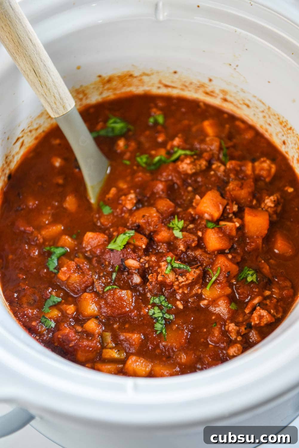 while slow cooker of turkey chili with shredded cilantro on top