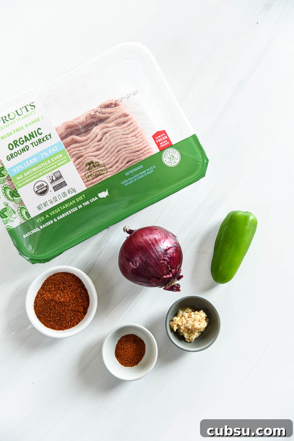 package of ground turkey, a red onion, a jalapeño pepper and ramekins of spices and garlic