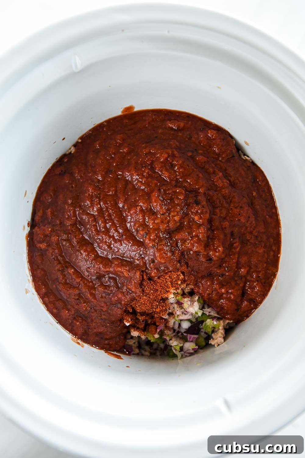crushed tomatoes over chopped peppers and onions in slow cooker