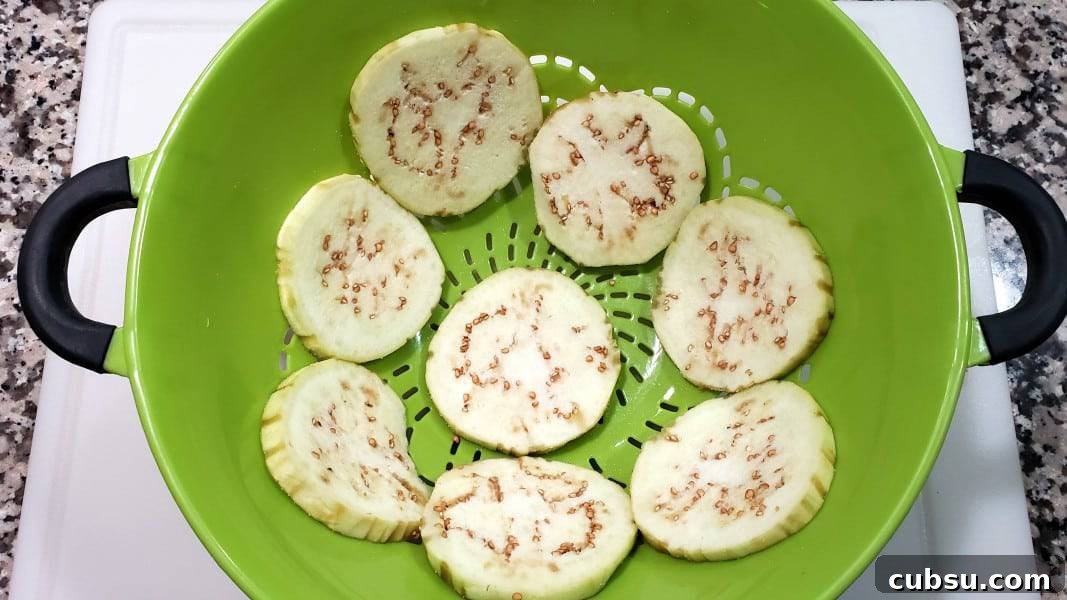Crispy Oven-Baked Eggplant Parmesan Recipe 3 8 slices of eggplant sprinkles with salt sitting in a colander