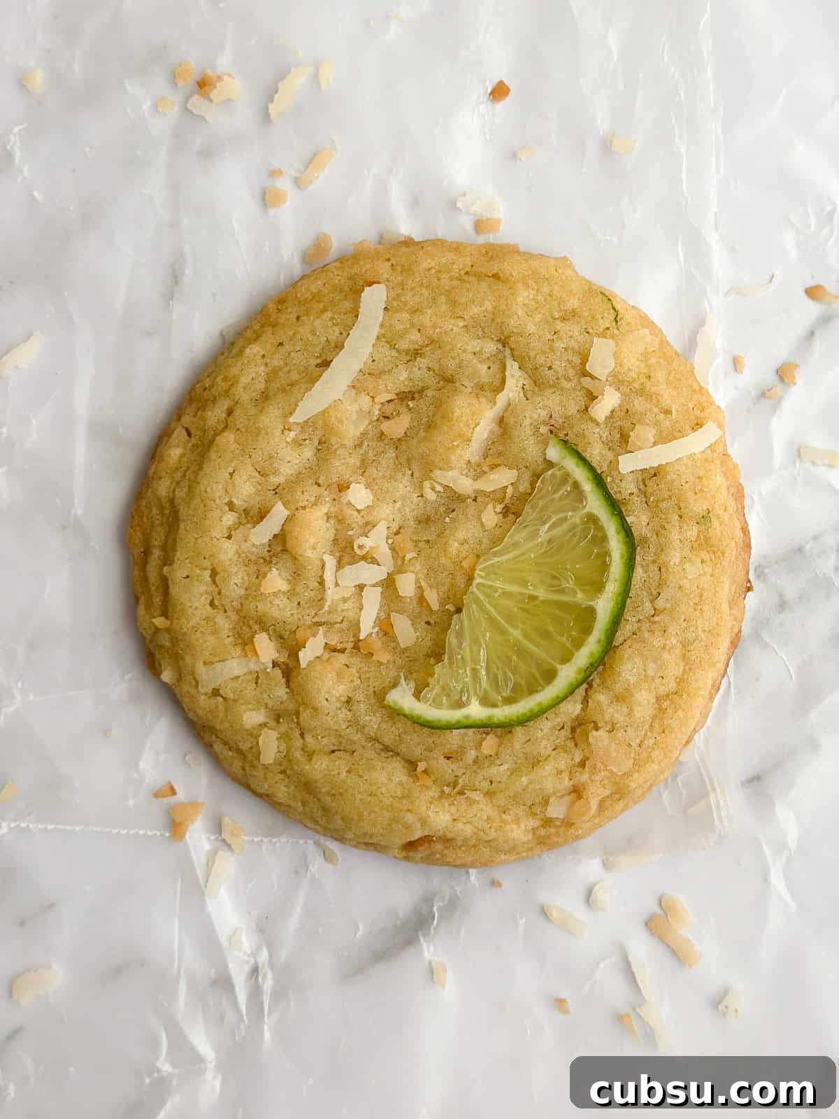 Zesty Lime Coconut Cookies Recipe for Fresh Tropical Flavor 3 a closeup of a single lime coconut cookie with a slice of lime on top.