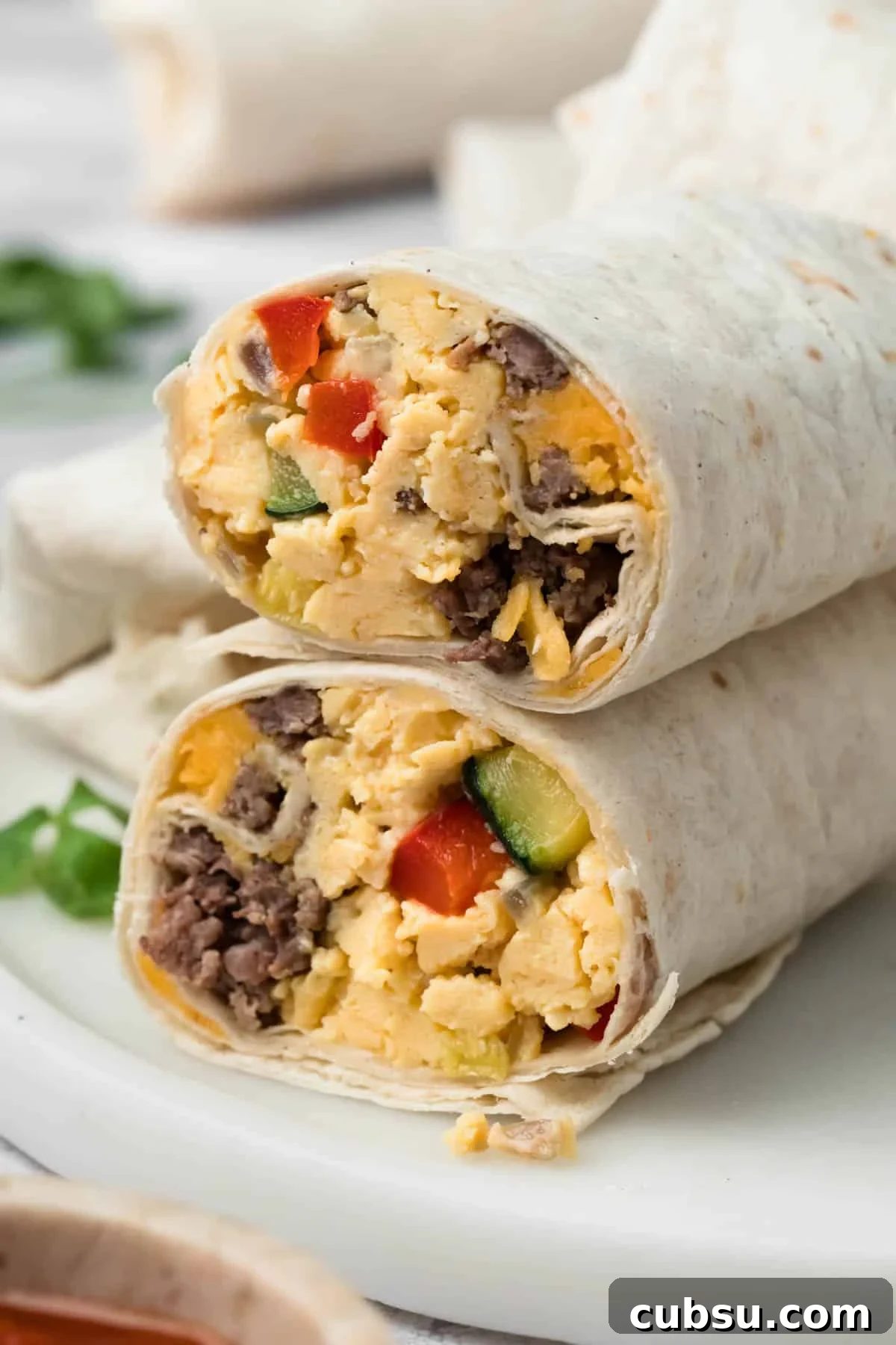 Make-Ahead Breakfast Burritos for Busy Mornings 2 side view of a halved breakfast burrito on a plate.