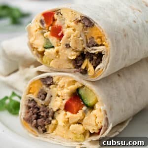 Make-Ahead Breakfast Burritos for Busy Mornings 15 side view of a halved breakfast burrito on a plate.