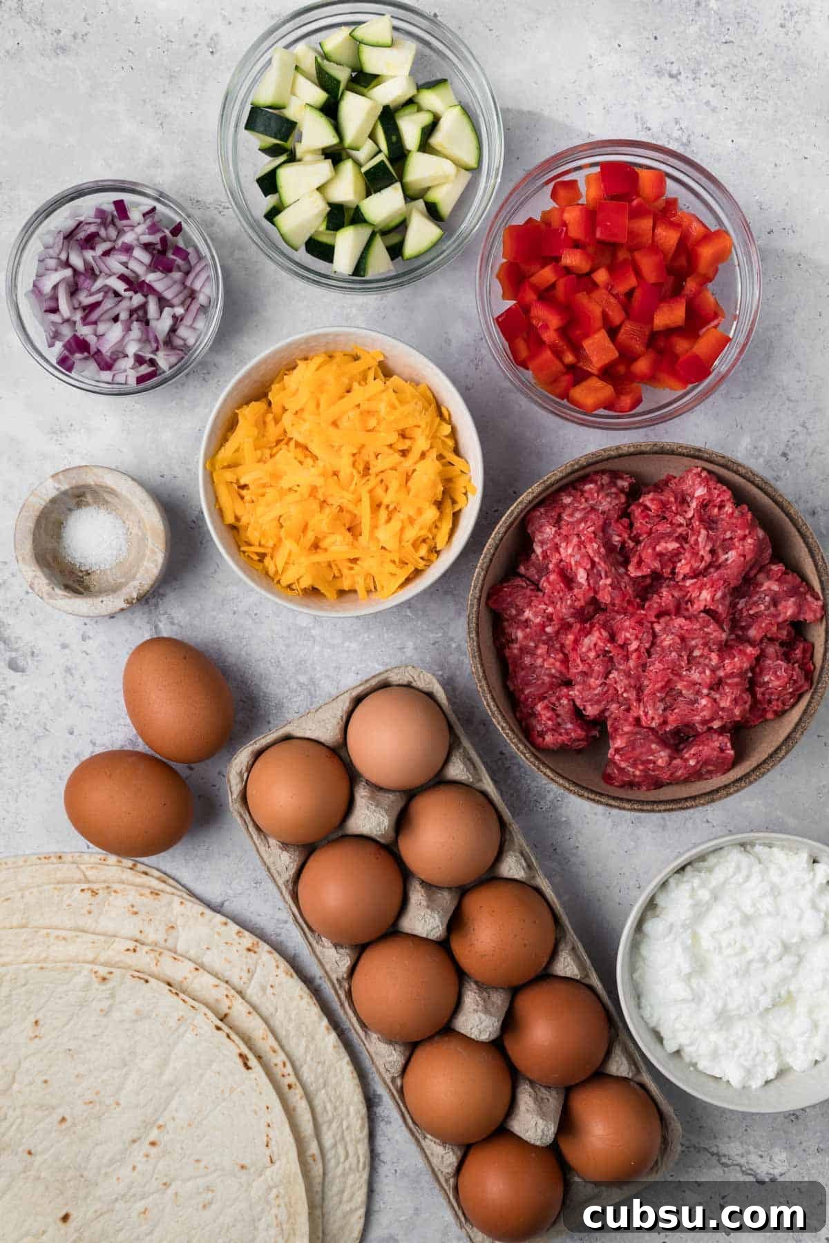 Make-Ahead Breakfast Burritos for Busy Mornings 4 overhead view of the ingredients for breakfast burritos in individual bowls.