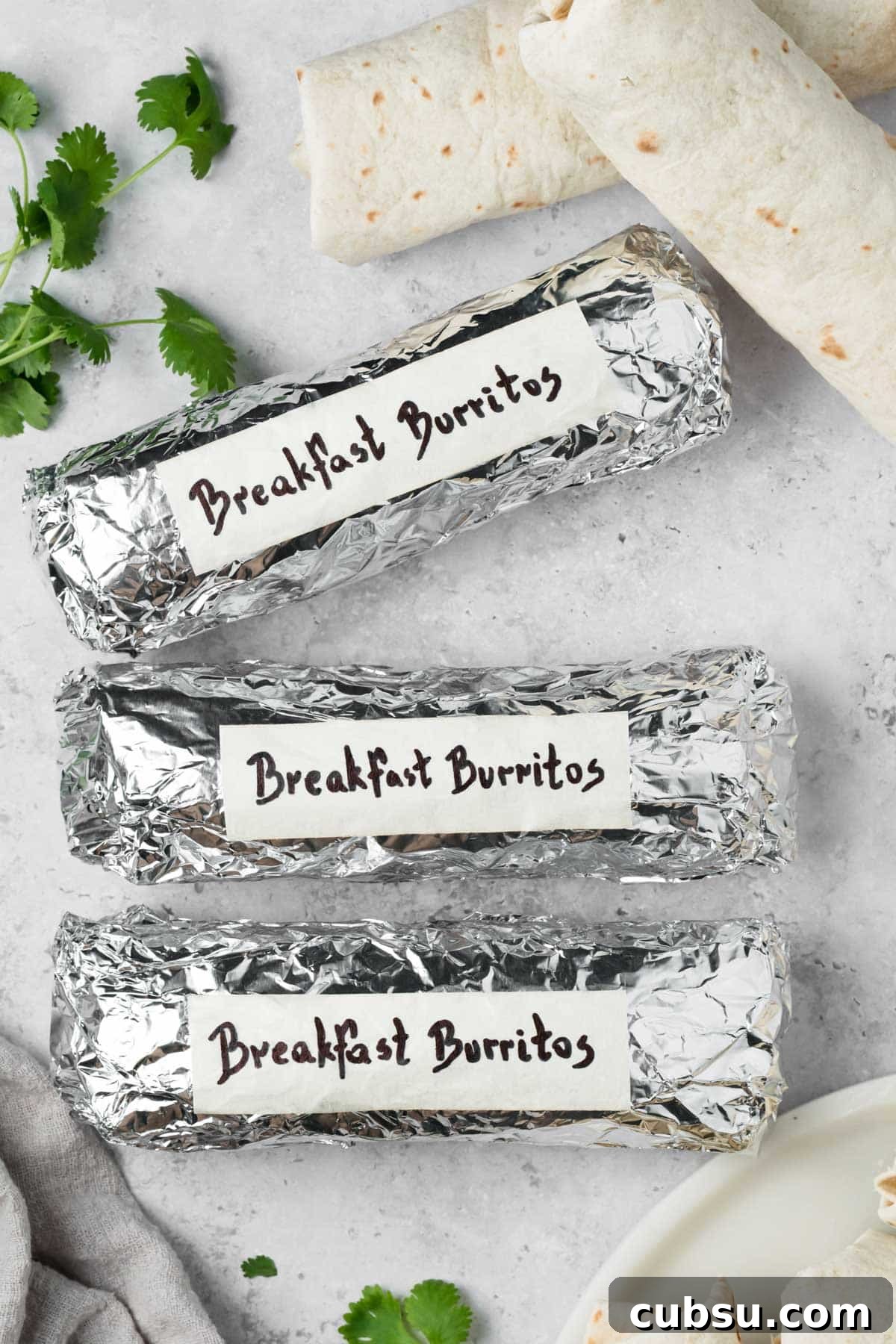 Make-Ahead Breakfast Burritos for Busy Mornings 9 overhead view of labeled breakfast burritos wrapped in foil.