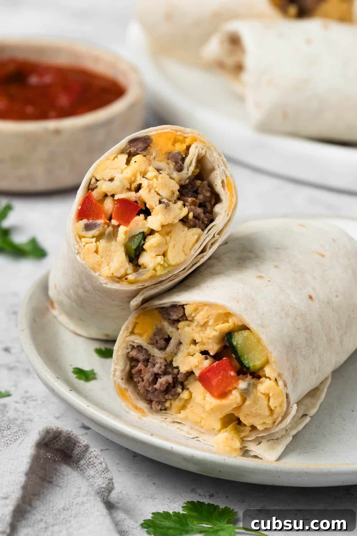 Make-Ahead Breakfast Burritos for Busy Mornings 10 side view of a halved breakfast burrito on a plate.