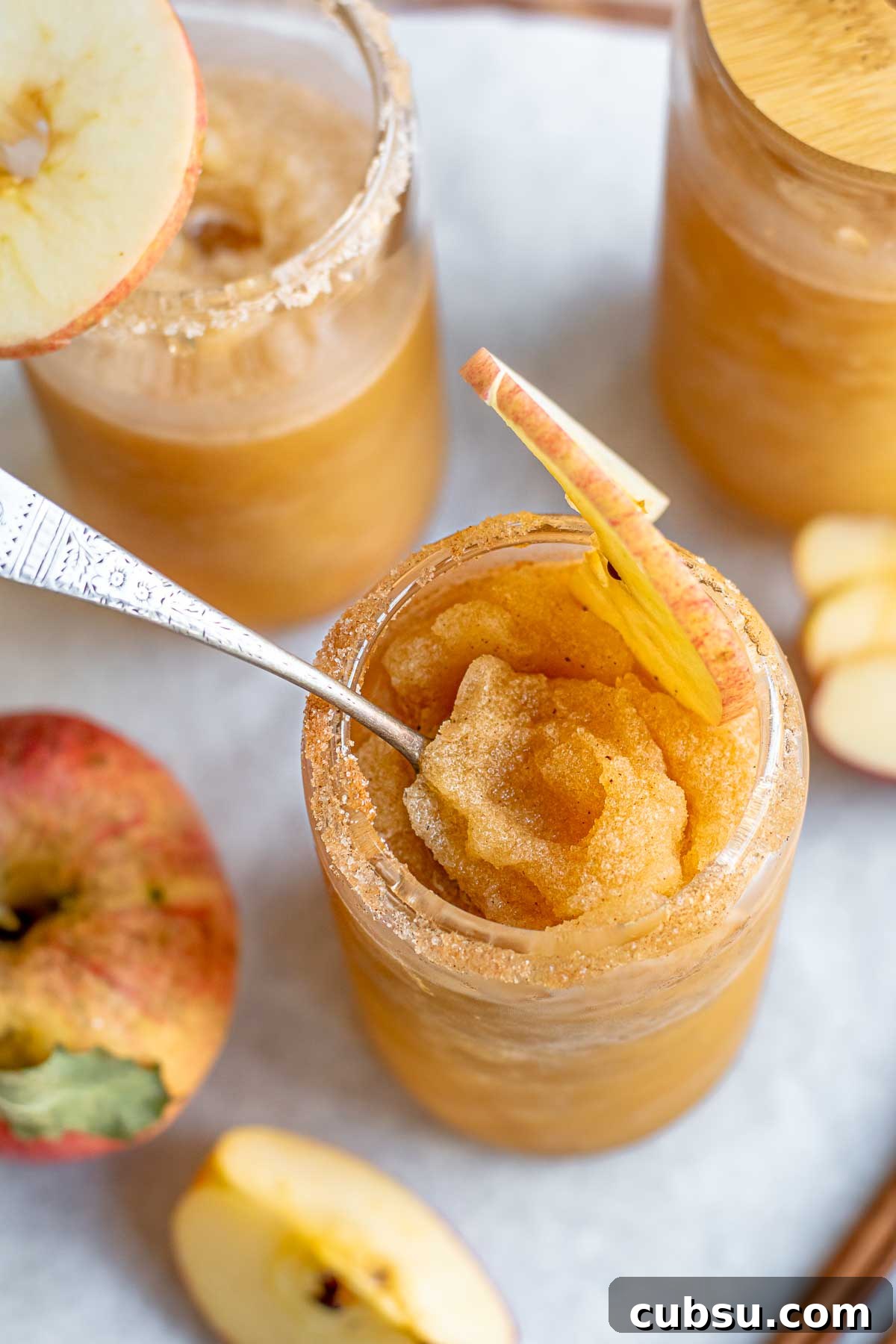 Spiced Apple Cider Slushies — Boozy or Virgin Recipes for Fall 11 A spoon sits inside an apple cider slushie in a glass.