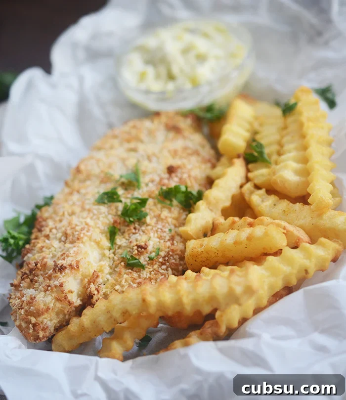 Crispy Air Fryer Fish and Chips Recipe for Perfect Crunch 5 Air fryer fried breaded fish with french fries on parchment paper garnished with parsley.
