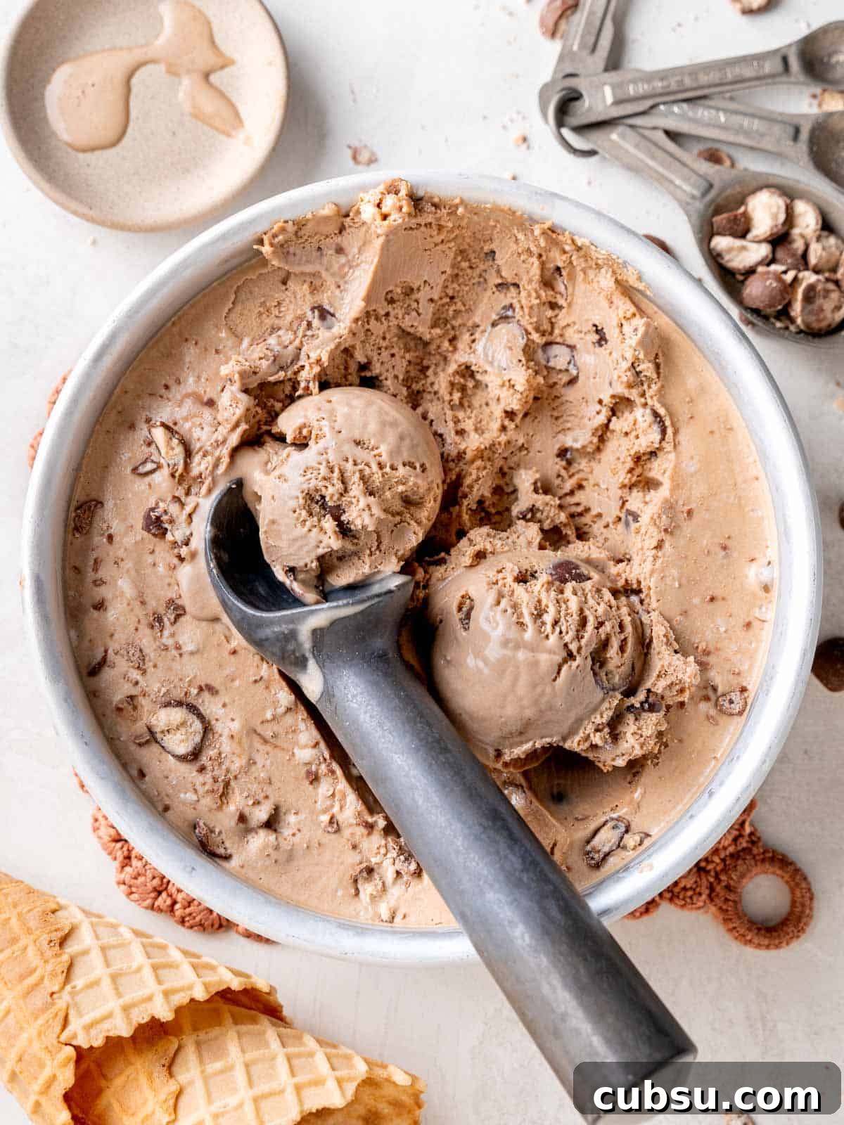 Top view of scoops of malted chocolate ice cream with Whoppers in a round pan.