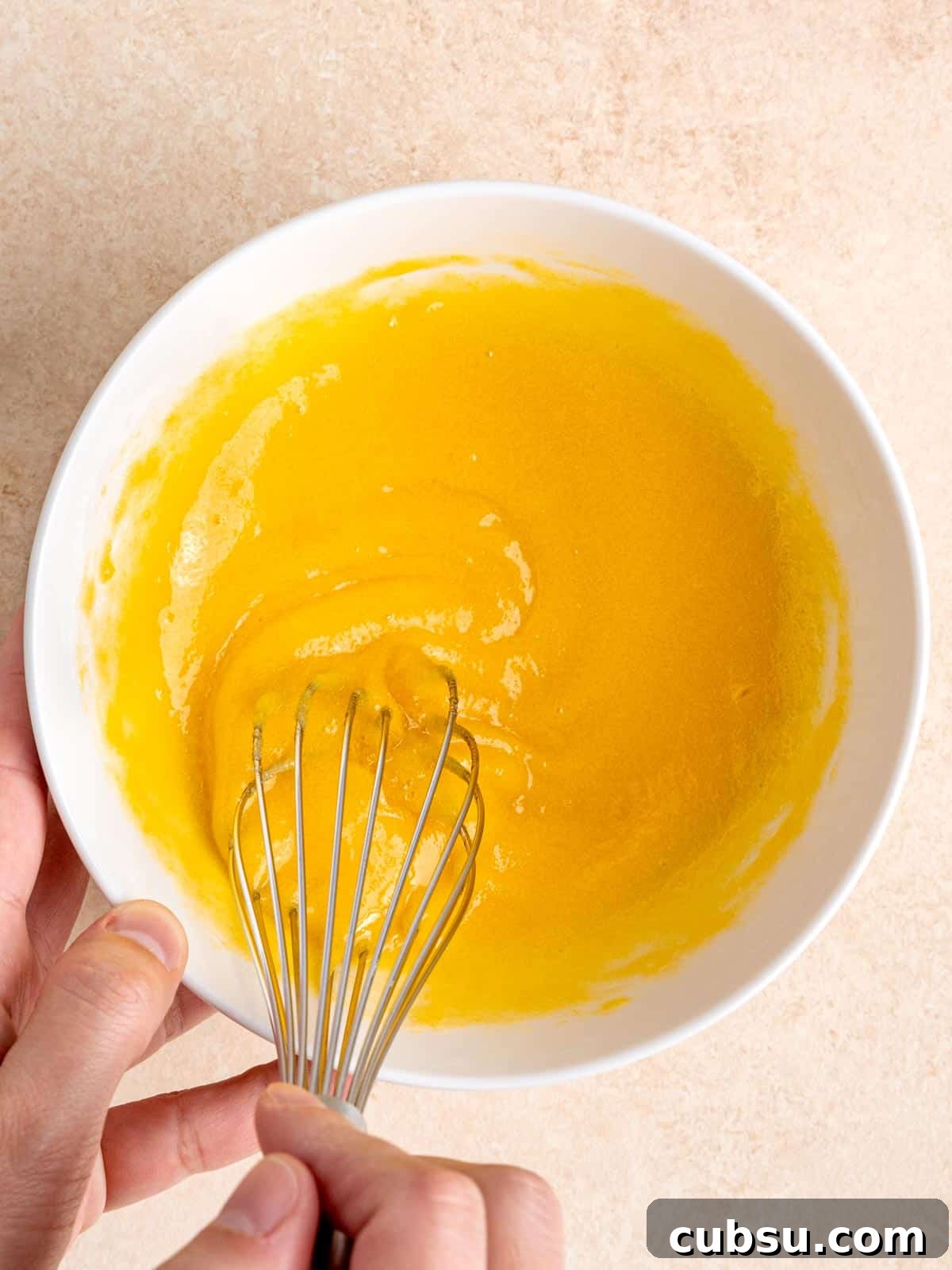 Whisking egg yolks and sugar in a bowl.