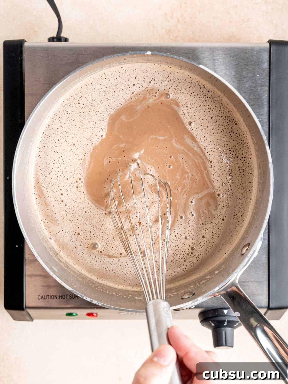 Whisking chocolate malt ice cream mixture in a pot.