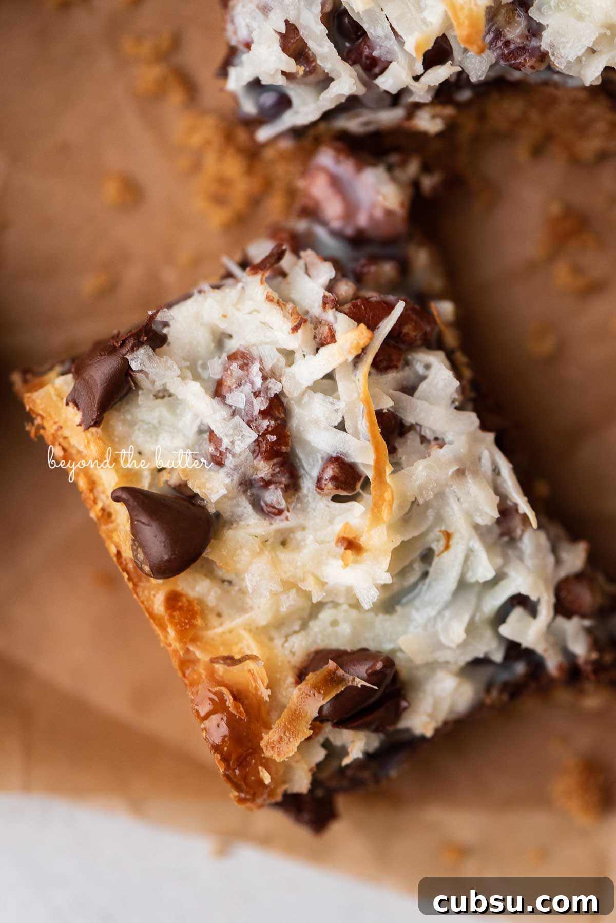 7-Layer Magic Cookie Bars Recipe: Simple Crowd-Pleaser 2 Magic cookie bars on brown parchment paper