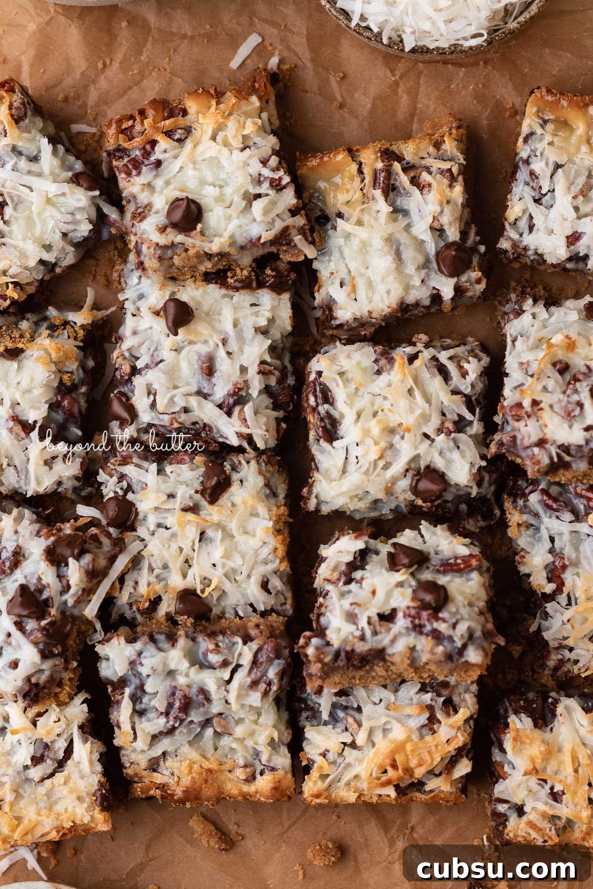 7-Layer Magic Cookie Bars Recipe: Simple Crowd-Pleaser 3 7 layer magic cookie bars on brown parchment paper