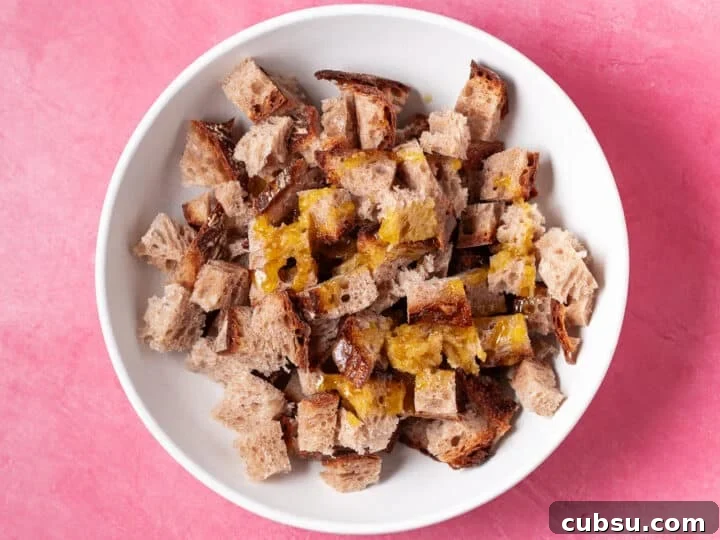 Cubed sourdough bread in a bowl with melted butter and oil for homemade croutons