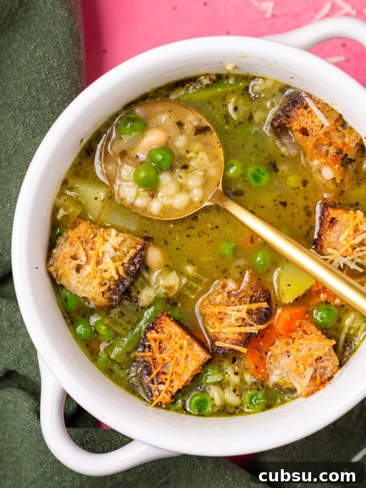 Close-up of minestrone soup with pesto, white beans, pearl couscous, peas, and parmesan croutons