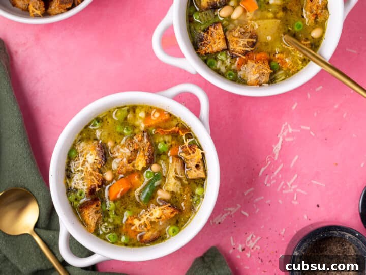 Wide overhead view of two bowls of minestrone soup with pesto and homemade croutons