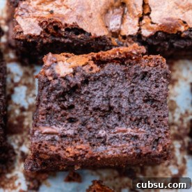 One-Bowl Gluten-Free Brownies: Fudgy Recipe for Chocolate Lovers 9 A gluten-free chocolate brownie on its side on a piece of baking paper with others from above