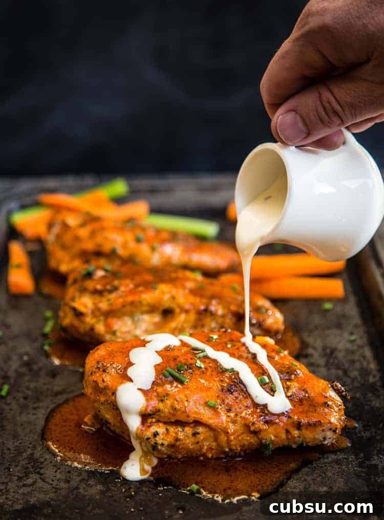 Buffalo stuffed chicken breasts on a platter with ranch being drizzled over the top.