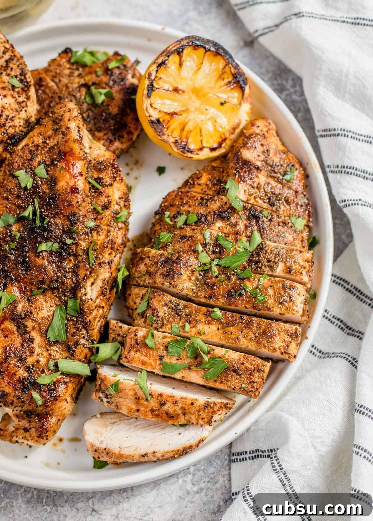 Grilled boneless and skinless chicken breast sliced on a plate.