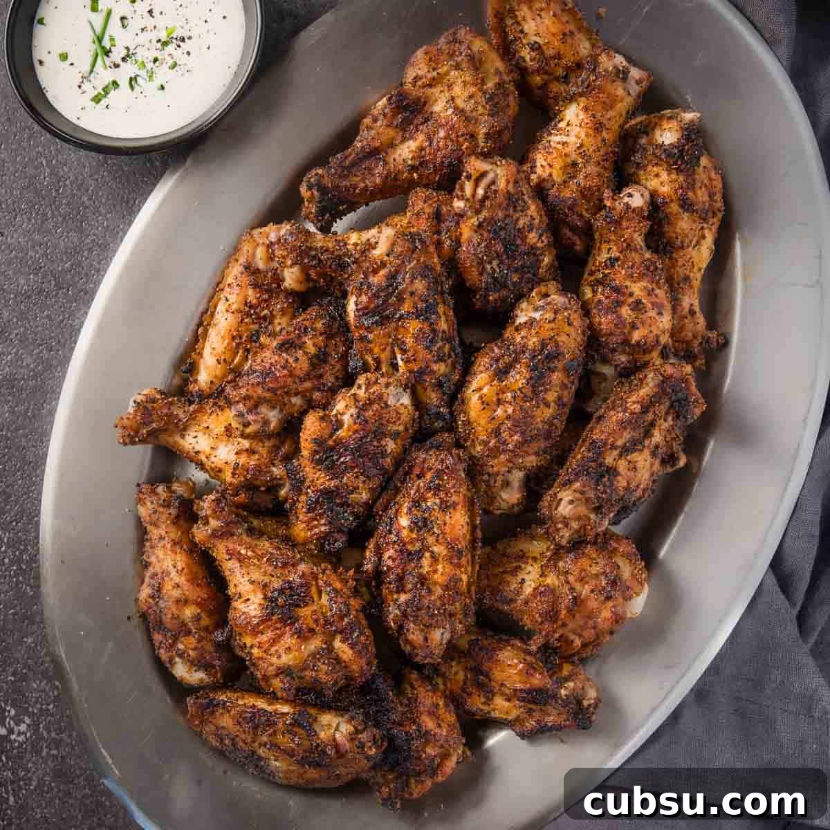 Dry Rub Chicken Wings on a platter next to a bowl of homemade ranch dressing