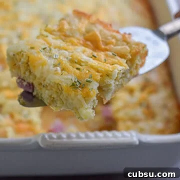 A pie cutter is holding a piece of the bisquick breakfast casserole over the casserole dish.