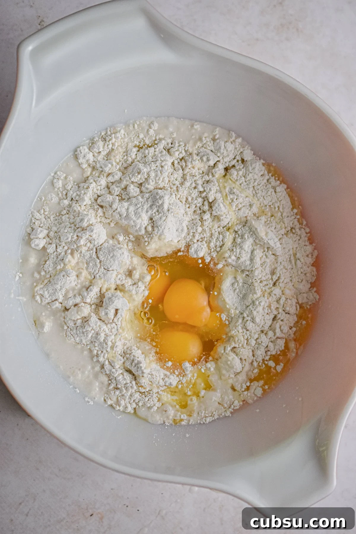 The eggs are added to the large mixing bowl.