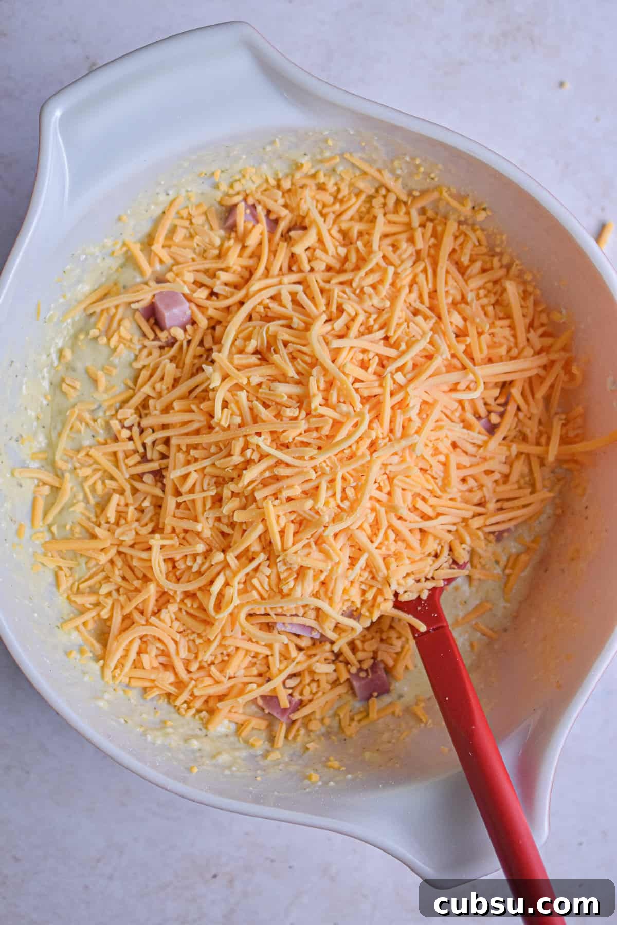 The cheese is added to the large mixing bowl.
