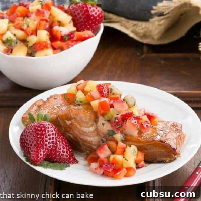 Strawberry Salsa Topped Salmon - Roasted Asian inspired salmon topped with fruit salsa. A delectable heart healthy entree Strawberry Salsa Topped Salmon garnished with fresh strawberries on a white plate