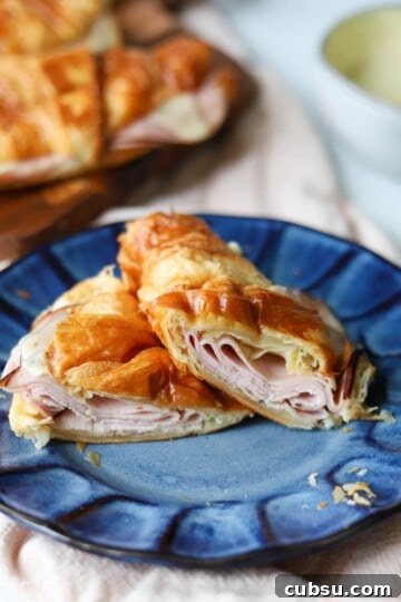 Ham and cheese croissant sliced in half on plate.