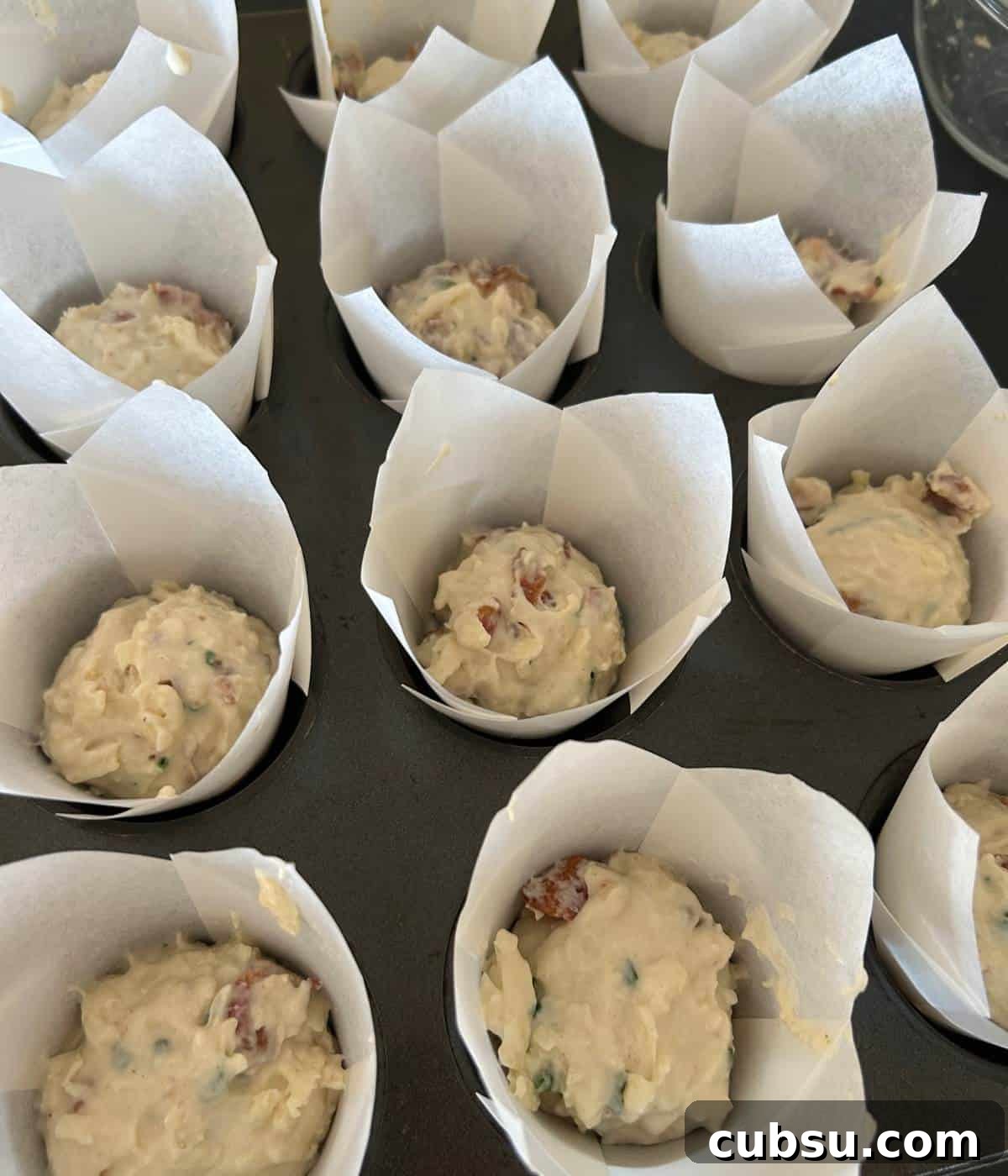 Savory Bacon and Cheese Muffins for Brunch or Snacks 8 Batter in liners in muffin tin.