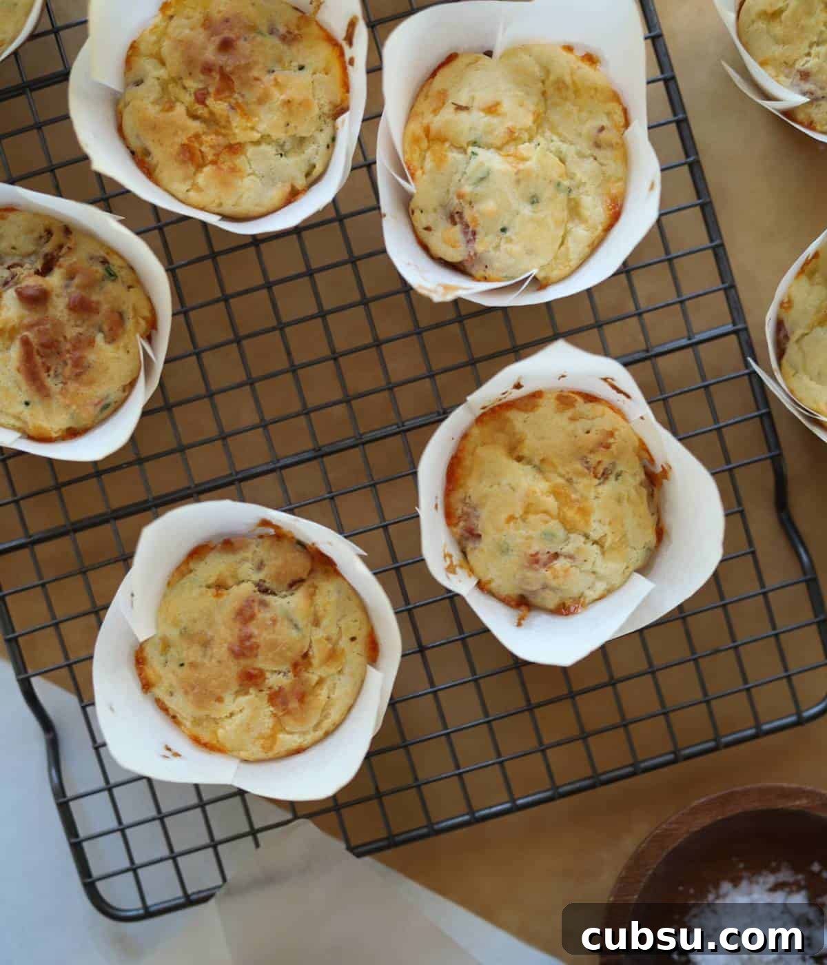 Savory Bacon and Cheese Muffins for Brunch or Snacks 9 Bacon muffins in tulip liners on baking rack.