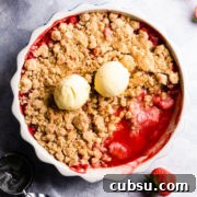 strawberry crumble in a baking dish and two scoops of ice cream on top.