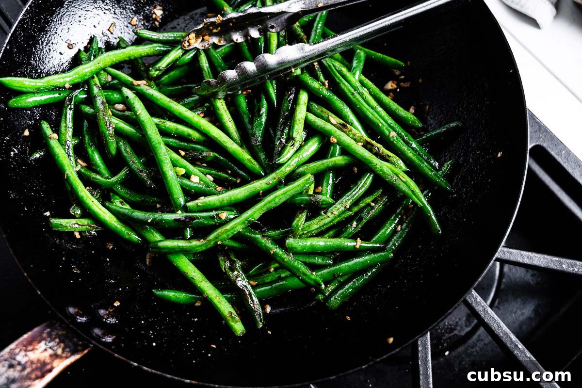 sauteeing green beans in a skillet with garlic