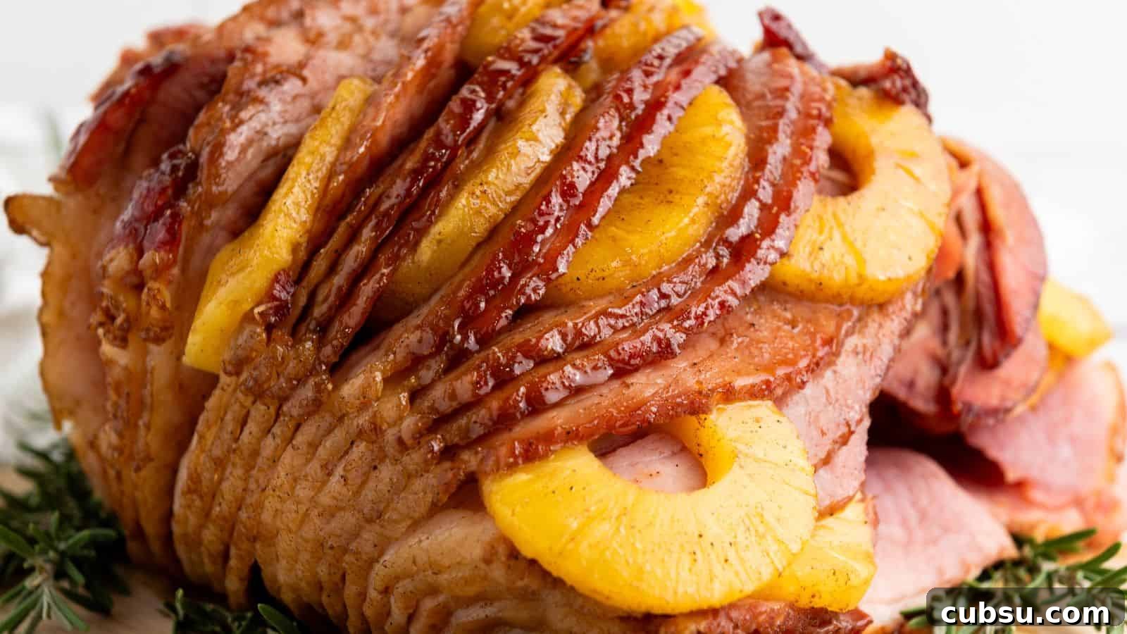 7 Holiday Ham Recipes to Make Dinner Feel Just Right 3 Glazed ham layered with pineapple slices and a hint of brown sugar, garnished with rosemary sprigs.